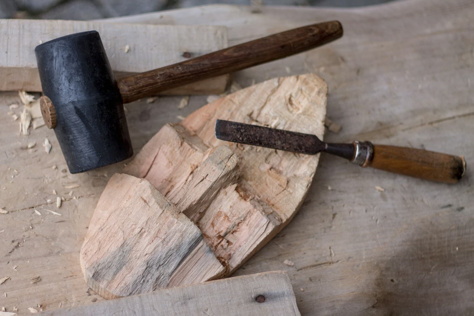 A sharp chisel resting on a wooden board next to a mallet