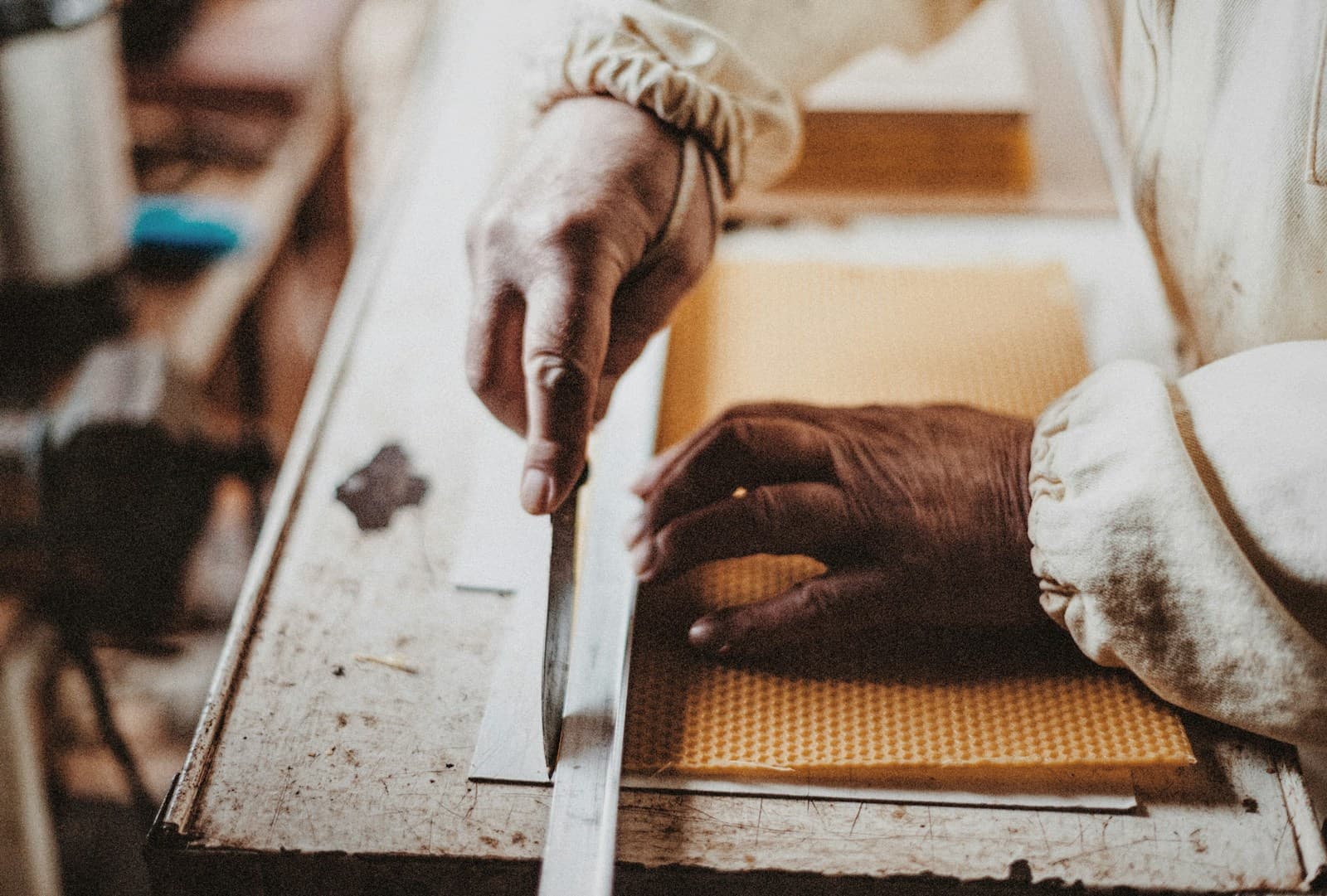 Weathered hands carefully carving a piece of wood with a chisel